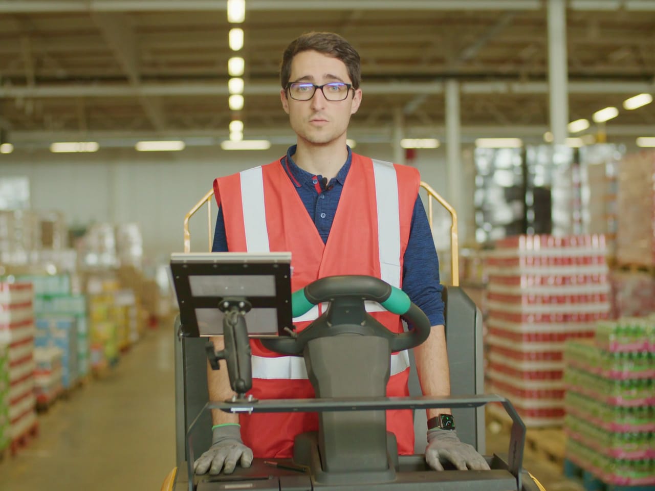 Préparateur de commandes en gilet sur son engin, dans l'entrepôt Aldi
