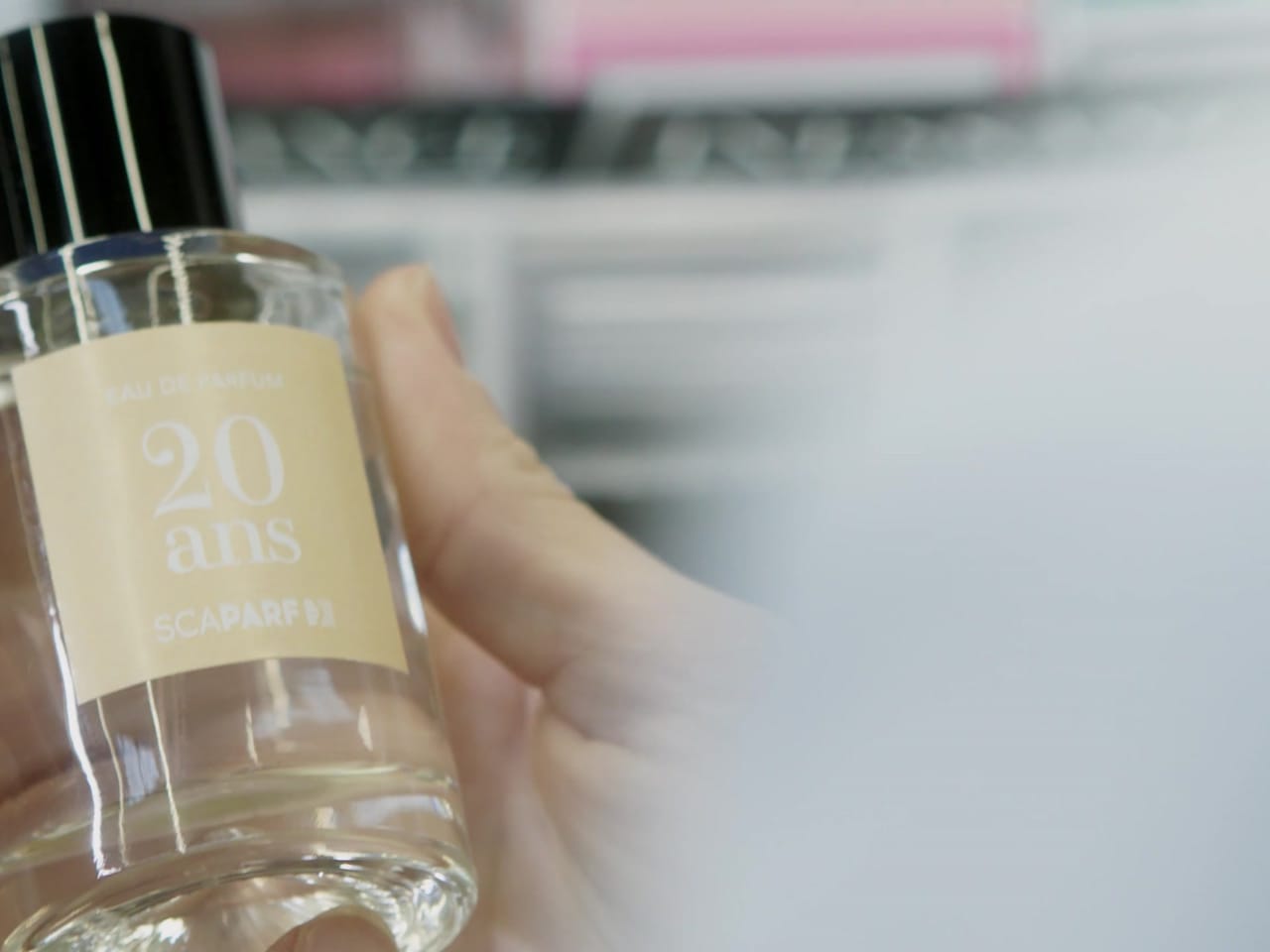 Gros plan publicitaire sur un flacon de parfum tenu en main